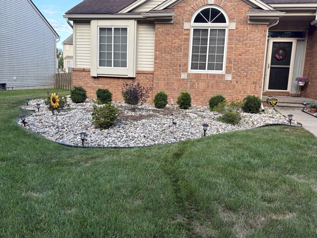 Rock bed installation with edging and shrubs